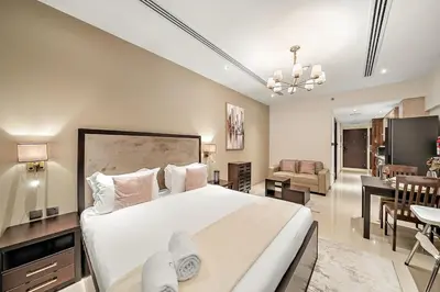 a bedroom with a large bed and a living room at FIRST CLASS Studio Cozy with City Vibes in Dubai