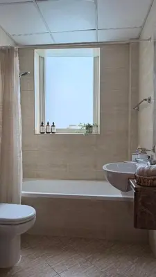 a bathroom with a tub and a toilet and a sink at Dar Al Noor Apartment in Dubai