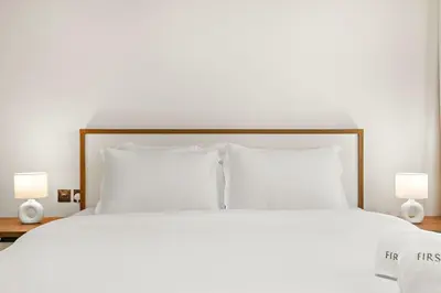 a bed with white pillows and two lamps at FIRST CLASS 1BR Minimalist Elegance in Dubai