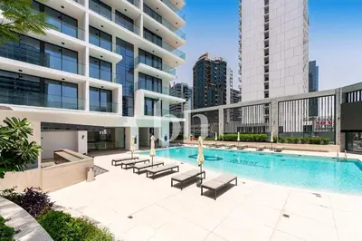 a large building with a swimming pool with lounge chairs at Chic 1-Bedroom Retreat in Heart of Business Bay in Dubai