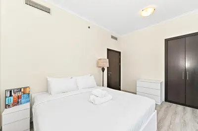 a white bedroom with a white bed and a cabinet at Torch Dubai Marina 2BDR with Pool Gym and Views in Dubai