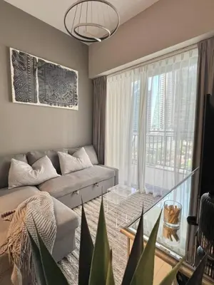 a living room with a couch and a large window at Cozy 1BR in Zada Tower Business Bay in Dubai