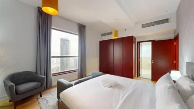 a bedroom with a bed and a chair and a window at Vacationer I Luxury 2 Bedroom Apartment I Marina View I Steps from JBR Beach in Dubai