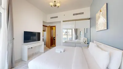 a white bedroom with a large bed and a television at Vacationer l 1 Bedroom Perched on the 19th Floor l Free Pool, Gym Access in Dubai