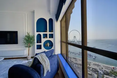a room with a blue couch and a large window at Full Ocean & Palm Views Apartments in JBR Beachfront with Dubai Eye Views in Dubai