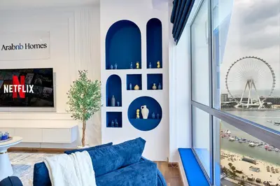 a living room with a blue couch and a large window at Full Ocean & Palm Views Apartments in JBR Beachfront with Dubai Eye Views in Dubai