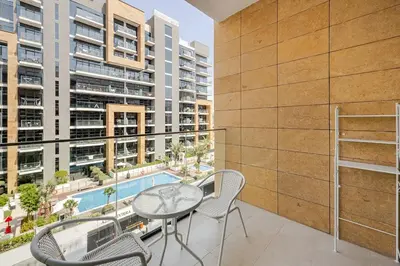 a balcony with a table and chairs and a pool at Ramaira Homes Azizi Riviera 26 by Vacay Xeal in Dubai