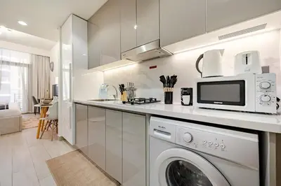 a kitchen with a washing machine and a microwave at Ramaira Homes Azizi Riviera 26 by Vacay Xeal in Dubai
