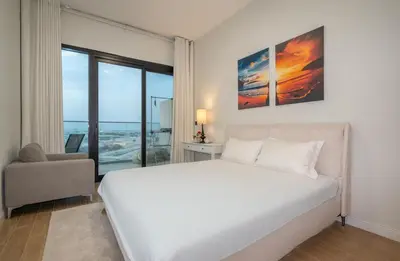 a bedroom with a large white bed and a chair at Stylish 1BR Just 3 Minutes Walk to Metro in Dubai