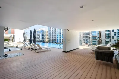 a living room with chairs and a pool in a building at Studio Near Ras Al Khor Wildlife Sanctuary with Partial Creek Views, Just Minutes from Downtown Attractions, Wilton Park Residences, Sobha Hartland by Deluxe Holiday Homes in Dubai