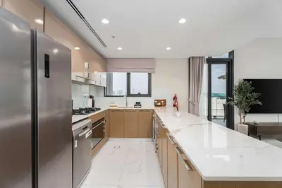a large kitchen with white marble counter tops at Elegant 3BR & City Skyline View Azizi Greenfield in Dubai