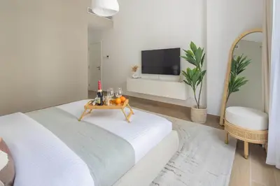 a white bedroom with a bed with a table at Frank Porter - La Sirene, Jumeirah in Dubai