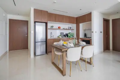 a kitchen with a wooden table and white chairs at Frank Porter - Palace Beach Residence Tower 1 in Dubai