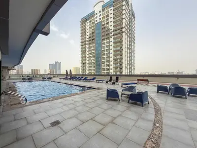 a swimming pool with blue chairs and a building at Frank Porter - Hera Tower in Dubai