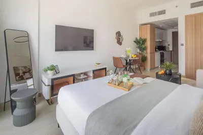 a bedroom with a large white bed and a living room at Frank Porter - Elysee III by Pantheon, JVC in Dubai