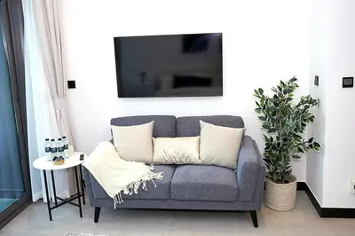 a gray couch with pillows in a living room at Cozy Studio, All Bills Included in Dubai