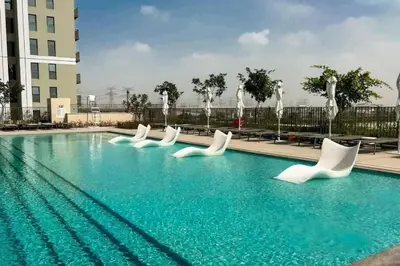 a swimming pool with white chairs and water fountains at Elegant 2BR Apartment in Socio Tower - Dubai Hills in Dubai