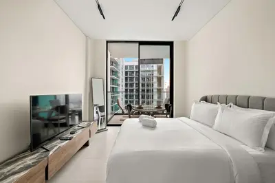 a white bedroom with a large bed and a tv at FIRST CLASS Studio Cozy Hideaway in Dubai