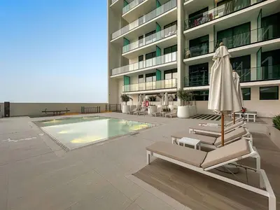 a large building with a pool and chairs and an umbrella at FIRST CLASS Studio Cozy Hideaway in Dubai