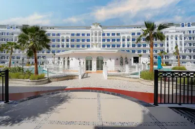 a large white building with palm trees in front of it at Livin' Holidays - 1 BR - Next to Miracle garden in Dubai