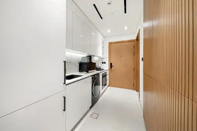 a kitchen with white cabinets and a hallway at FIRST CLASS Studio Cozy Luxury Escape in Dubai