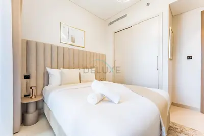 a white bedroom with a large bed and a table at Modern Apartment Near Sobha Hartland Amenities, Minutes from Ras Al Khor Wildlife Sanctuary and Downtown Dubai, Sobha Creek Vistas Tower A, Sobha Hartland by Deluxe Holiday Homes in Dubai