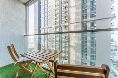 a table and chairs on a balcony with a large window at Modern Apartment Near Sobha Hartland Amenities, Minutes from Ras Al Khor Wildlife Sanctuary and Downtown Dubai, Sobha Creek Vistas Tower A, Sobha Hartland by Deluxe Holiday Homes in Dubai