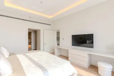 a white bedroom with a bed and a tv at Daniels 1BR with Sea View at The Palm Tower in Dubai