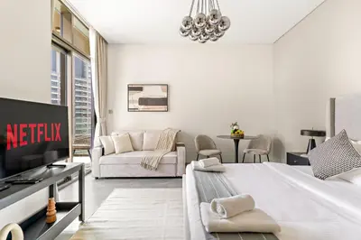 a white living room with a bed and a couch at VayK - Elegant Canal View studio in Business Bay in Dubai