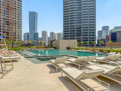 a pool with lounge chairs and a city skyline at VayK - Elegant Canal View studio in Business Bay in Dubai
