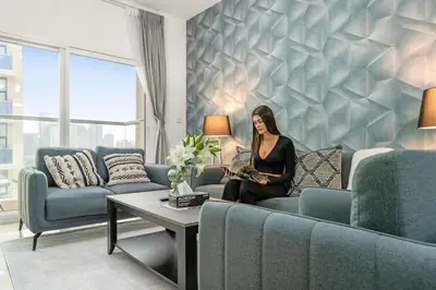 a woman sitting on a couch in a living room at Charming 1BR with Balcony and City View in JVC in Dubai
