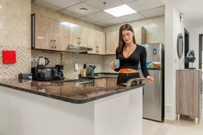 a woman standing at a counter in a kitchen at Charming 1BR with Balcony and City View in JVC in Dubai