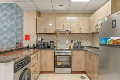 a kitchen with wooden cabinets and a stove top oven at Charming 1BR with Balcony and City View in JVC in Dubai