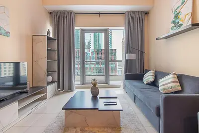 a living room with a blue couch and a large window at Modern 1-Bedroom Apartment in Bay Central Tower 1 in Dubai