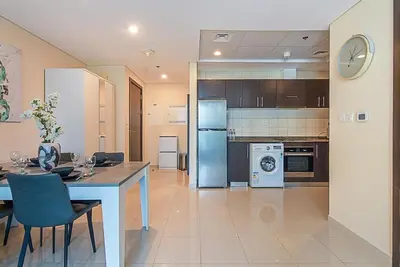 a kitchen with a dining table and a refrigerator at Modern 1-Bedroom Apartment in Bay Central Tower 1 in Dubai