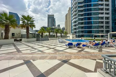 a pool with people laying in lounge chairs next to a building at Modern 1-Bedroom Apartment in Bay Central Tower 1 in Dubai