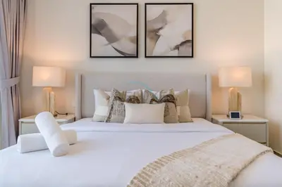 a bedroom with a white bed with two lamps at Breathtaking Burj Khalifa Views from a High-Floor 3BR with an Assistant Room, Just Minutes from Dubai Mall and Downtown Attractions, Imperial Avenue, Downtown Dubai by Deluxe Holiday Homes in Dubai