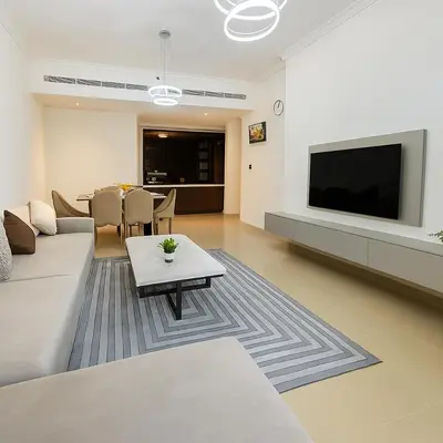 a living room with a couch and a tv and a table at Sunset Beach Escape at Palm Jumeirah 2BR 241 by The Rosewood Vacation Homes Rental LLC in Dubai