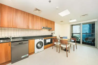 a kitchen with wooden cabinets and a table and chairs at PVH - Sea View 3BR and Maids Room - Princess Tower in Dubai
