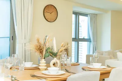 a dining room table with a clock on the wall at PVH - Sea View 3BR and Maids Room - Princess Tower in Dubai
