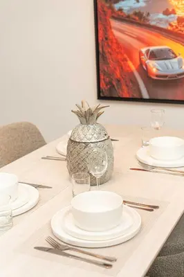 a table with white plates and a pineapple on it at PVH - Stunning 2BR - Creek Vistas Grande in Dubai