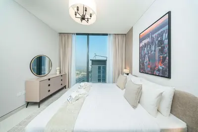 a bedroom with a large white bed with a large window at PVH - Stunning 2BR - Creek Vistas Grande in Dubai