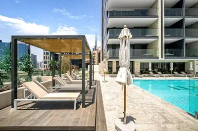 a pool with chairs and an umbrella next to a building at FIRST CLASS Studio Canal and Pool View in Dubai
