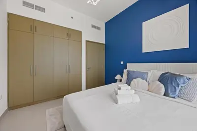 a bedroom with a large white bed with a blue wall at Luxury Seaview Apartment Near Bluewaters & JBR in Dubai