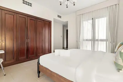 a bedroom with a large white bed and wooden cabinets at FIRST CLASS 1BR Cozy Old Town Escape in Dubai