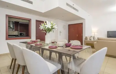 a dining room with a table and white chairs at Rimal 1 JBR Beach Access 3 BR in Dubai