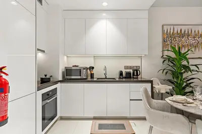 a kitchen with white cabinets and a table at FIRST CLASS 1BR Cozy Luxe Escape in Dubai