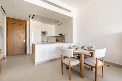 a kitchen and dining room with a table and chairs at Serene 1BR Retreat with Pool & Gym by Safa Park in Dubai