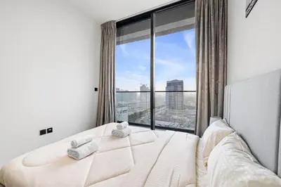 a bedroom with a bed and a large window at BLVD Luxe Stay with Pool Heart of JVC in Dubai