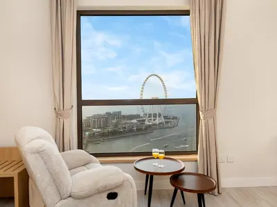 a living room with a chair and a large window at Luxurious 2BHK Sea & Dubai Eye View in Dubai